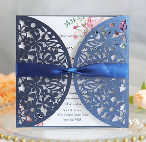 Detail of laser-cut navy blue wedding invitation with a silk ribbon and floral liner