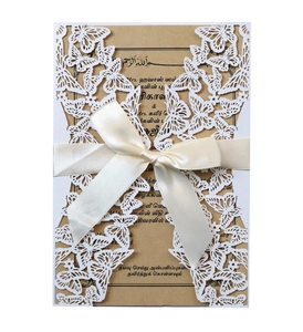 Detail of laser-cut butterfly invitation featuring a cream ribbon bow and kraft insert