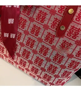 Detail of red brocade tote bag with Xi character jacquard and leather handle straps