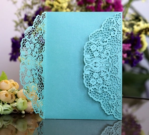 Macro shot of laser-cut lace pattern on light blue pearlescent wedding invitation cover