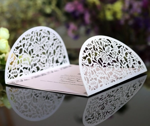 Elegant white laser-cut floral wedding invitation with pink inner card and leaf patterns