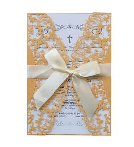 Detail of laser-cut wedding invitation with elegant gold cover and satin ribbon bow