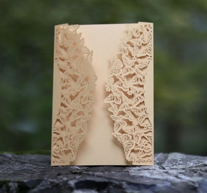 Detailed laser-cut butterfly invitation card in champagne gold on natural rock
