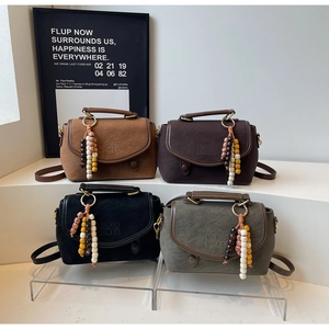 Detail of vintage matte leather crossbody bags with tassel charms in earthy tones