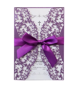 Detail of purple laser cut wedding invitation with ornate patterns and satin ribbon bow