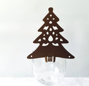 Brown laser-cut Christmas tree wine glass card decoration on white plush surface