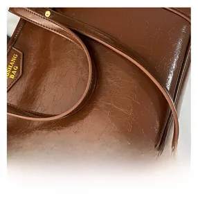 Detailed macro view of dark brown oil wax leather texture and golden embossed logo label