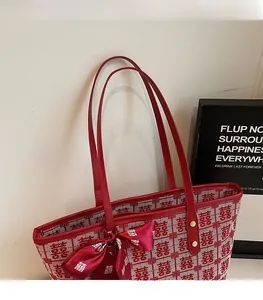 Close-up of red festive tote bag featuring traditional Xi character and silk bow detail