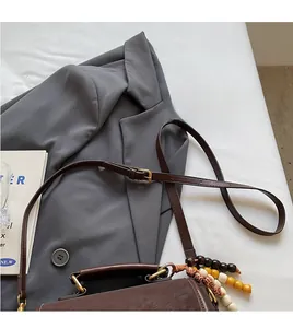 Detail of vintage dark brown crossbody bag with wooden bead charm and long strap