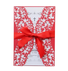 Detail of red laser-cut wedding invitation with lace vine pattern and satin ribbon bow