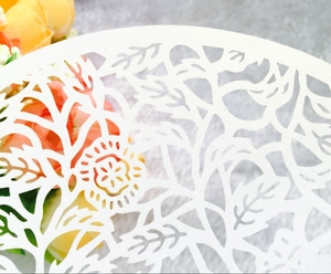 Intricate laser-cut floral pattern on white cardstock for elegant wedding invitations