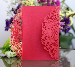 Detail of red laser-cut wedding invitation cover with intricate floral lace pattern