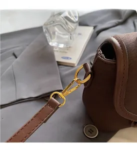 Detail of dark brown leather handbag with gold-tone hardware and litchi texture