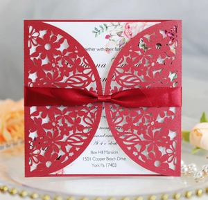 Detail of red laser-cut wedding invitation with silk ribbon and floral inner card