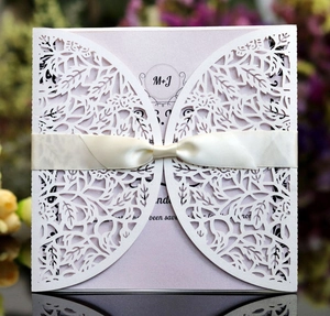 Detail of laser-cut floral invitation with pink inner card and cream satin ribbon bow
