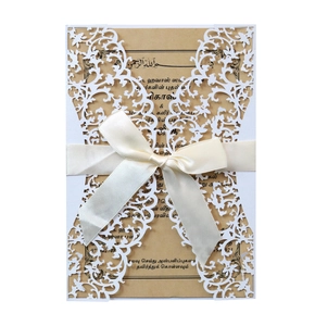 Elegant white laser-cut wedding invitation with cream ribbon and kraft paper insert