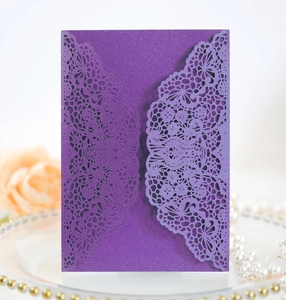 Macro shot of dark purple laser-cut lace wedding invitation with pearl decorations