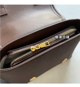 Detail of premium gold metal zipper on dark brown leather bag with soft lining