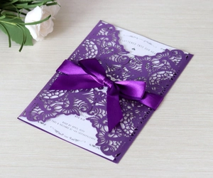 Detailed view of purple laser cut wedding invitation with ribbon and printed insert