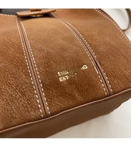Vue macro de la texture du cuir marron rétro et des détails du logo doré brodé
