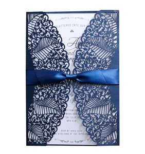 Detailed laser cut navy blue wedding invitation with elegant satin ribbon bow and insert