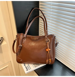 Detail of dark brown vintage faux leather tote with orange wood bead tassel charm