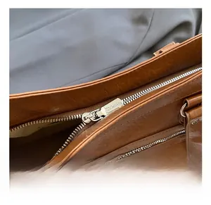Detailed macro view of the metal zipper and strap hardware on the brown tote bag