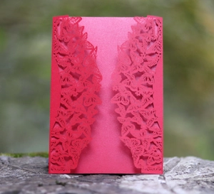 Detail of red laser-cut butterfly invitation card with intricate hollow pattern