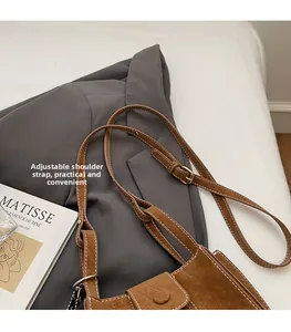 Détail du sac seau en daim marron avec surpiqûres blanches et bandoulière réglable