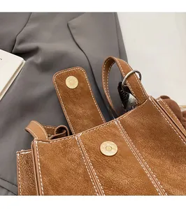 Détail du fermoir magnétique et surpiqûres sur le sac seau en daim marron