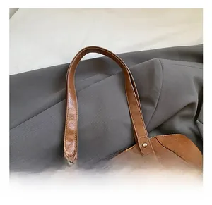 Close-up of caramel brown leather tote bag showing double handles and zipper details