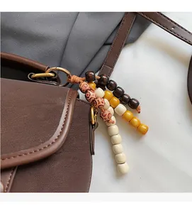 Detail of lychee pattern leather bag with gold rings and colorful wooden bead charms