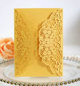 Close-up of golden laser-cut lace invitation with elegant floral patterns on gold cardstock