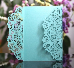 Macro detail of mint green laser-cut wedding invitation with elegant floral lace patterns