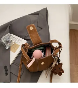 Vue détaillée de l'intérieur du sac seau marron avec téléphone, parapluie et portefeuille