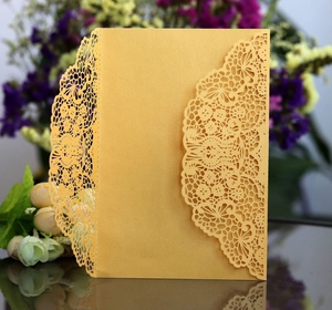 Close-up of golden laser-cut invitation card with intricate floral lace pattern detail