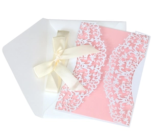 Elegant laser cut wedding invitation set with pink card, cream ribbon, and white envelope