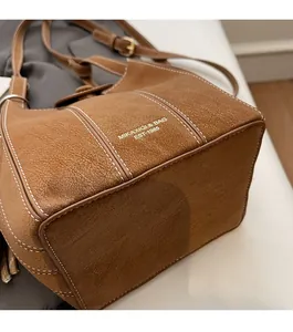 Gros plan sur la texture du cuir marron rétro avec des surpiqûres blanches sur ce sac