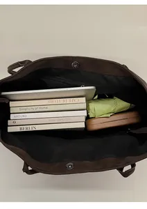 Spacious interior of a brown tote bag showing capacity for a laptop, books, and umbrella