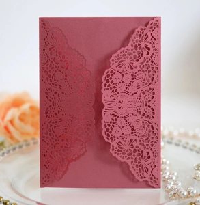 Detailed laser-cut lace texture on a burgundy wedding invitation with elegant floral hollows