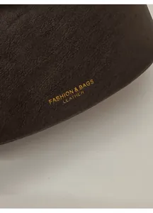 Close-up of brown leather bucket bag with gold stamped fashion and bags lettering