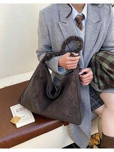 Detail of dark brown suede tote bag with ruched handle in vintage British style