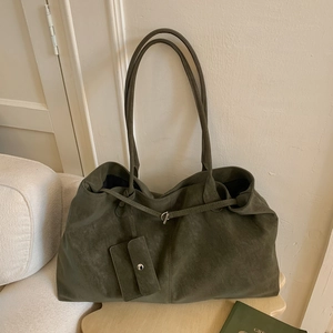 Detail of olive green suede tote bag with matching card holder pouch on beige sofa