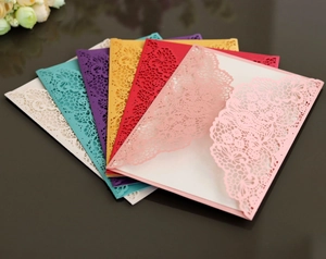 Detail showing various colors of laser-cut lace invitations with shimmering paper texture