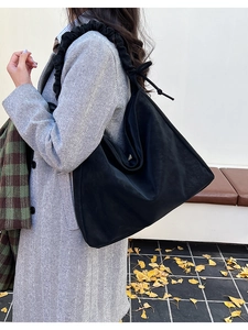 Detail of black suede hobo tote with scrunchie shoulder strap on model in winter coat