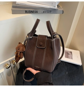 Detailed close-up of dark brown bucket bag with contrast stitching and teddy charm