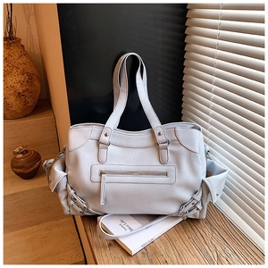 Close-up of light blue leather tote bag with side pockets and metal buckle on wooden table