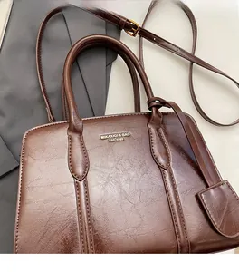 Detail of dark brown vintage briefcase with gold logo and adjustable shoulder strap