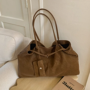 Detail of caramel brown matte tote bag with slim shoulder straps and matching mini pouch