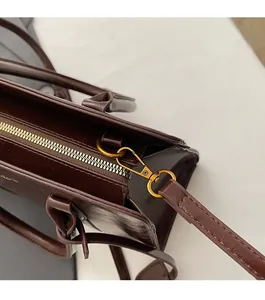 Detail of dark brown leather handbag featuring durable gold hardware and smooth zipper